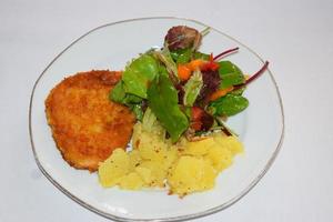 schnitzel med potatisar och sallad foto