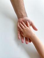 vuxen och barn håll deras händer tillsammans. fäder dag barn ger hand till vuxen foto