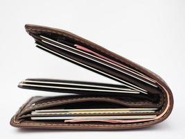 brun läder plånbok full av kreditera kort och röd Bank anteckningar på vit bakgrund foto