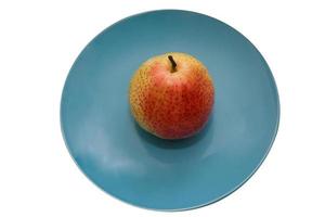 saftigt päron på en blå keramisk plattisolat på vit bakgrund foto
