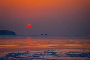 marinmålning isstrand och den röda solnedgången. foto