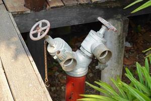 gammal röd brand brandpost på de trädgård. kran vatten för vatten tillförsel. foto