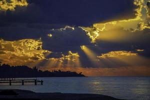 marinmålning med en ljus solnedgång och strålar genom molnen foto