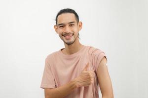 porträtt av asiatisk ung man, malel Tonårs attraktiv efter få, motta anti virus vaccin covid19. som visar ärm på bandage i tillfällig, isolerat på vit bakgrund, kopia Plats foto