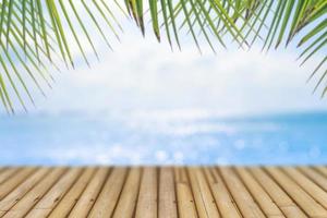 selektivt fokus på gammalt träbord med en suddig vacker strand med tropiska palmer för att visa din produkt. foto