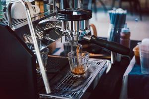 espresso maskin häller kaffe in i glas i Kafé. foto