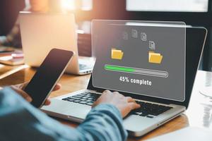 överföring av filer datasystem flyttkoncept, person hand som använder bärbar dator som väntar på överföringsfilprocessen med laddningsfältikonen på virtuell skärm. foto
