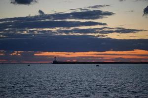 solnedgång i havsviken på lönelysten för den mörka himlen foto