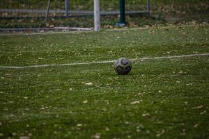 fotboll liggande på grön artificiell torva med höst löv foto