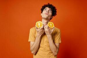 kille med lockigt hår apelsiner i händer frukt roligt röd bakgrund foto