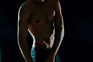 man med muskulös magmuskler beskurna se av Gym mörk bakgrund foto