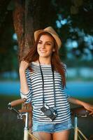 härlig ung kvinna i en hatt med en cykel i en parkera foto