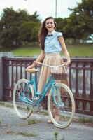 ung skön, elegant klädd kvinna med cykel i de parkera eller utomhus- foto