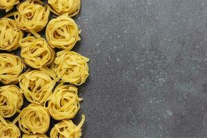 rå pasta tagliatelle med kopia Plats på betong bakgrund. foto