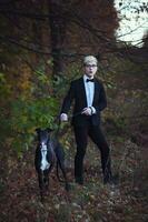 ung attraktiv man i kostym och slips med en vinthund hund i höst utomhus foto