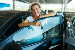 Lycklig kvinna stående nära en bil med nycklar i hand - begrepp av uppköp en Begagnade bil foto