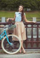 ung vacker, elegant klädd kvinna med cykel foto