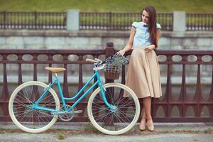 ung vacker, elegant klädd kvinna med cykel foto