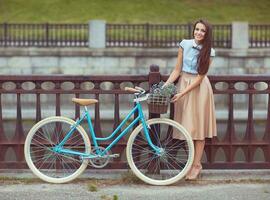 ung skön, elegant klädd kvinna med cykel utomhus- foto