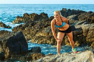 idrottare kvinna stående efter sport utövar på de stenar förbi de hav foto