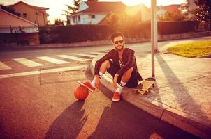 eleganta man i solglasögon med en basketboll och skateboard foto