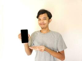 asiatisk ung man som visar smartphone med tom skärm foto