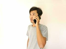 asiatisk ung man på de telefon med en smartphone isolerat på vit foto