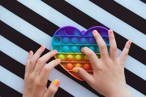 barn spelar med regnbåge pop- den fidget leksak. skjuta på bubbla fidget sensorisk leksak - tvättbar och återanvändbar kisel påfrestning lättnad leksak. antistress leksak för barn med särskild behov. foto