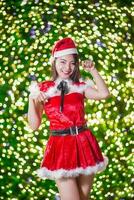 Söt asiatisk flicka i santa kostym för jul med natt ljus foto