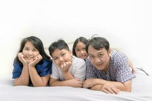 asiatisk Lycklig ung familj liggande i säng tillsammans foto