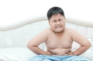 fet fett pojke övervikt magont på säng isolerat foto