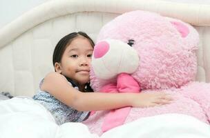 söt asiatisk liten flicka kramas stor rosa Björn foto