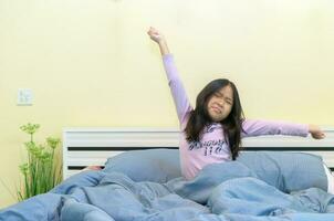 söt flicka stretching i säng efter vakna upp, foto