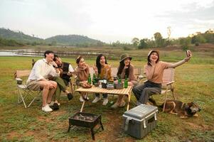 grupp av ung asiatisk människor är njut av camping i naturlig campingplats foto