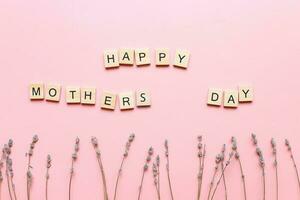 Lycklig mödrar dag. ett inskrift tillverkad av brev. flatlay moms dag på rosa bakgrund foto