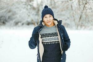stilig kille i en stickat Tröja med mönster och en vinter- jacka Framställ på en snöig dag foto