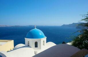 blå kupol av kyrka och blå hav vatten i santorini. foto