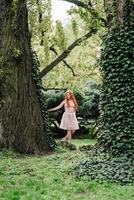 rödhårig ung flicka som går i en park mellan träd foto