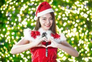 Söt asiatisk flicka i santa kostym för jul med natt ljus foto