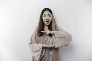 ett förvånad asiatisk muslim kvinna över isolerat bakgrund innehav kopia Plats imaginär på de handflatan till Föra in ett ad foto