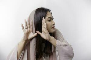 en nyfiken ung asiatisk muslim kvinna bär en huvud scarf påfrestande till höra du få höra lyssnande spänt isolerat på vit bakgrund foto