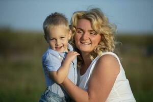 Lycklig mamma med henne son utomhus. blond europeisk stil kvinna kramar liten pojke. foto
