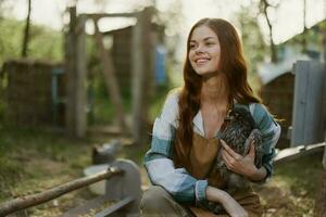 ung kvinna leende för de kamera innehav en kyckling och Lycklig arbetssätt på de bruka foto