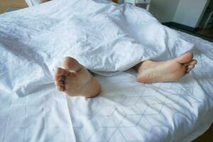 ung kvinna liggande med bar fötter i säng, foto