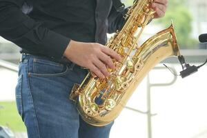 män händer spelar de saxofon utomhus. foto