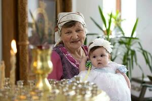 juli 15, 2020 belarus, stad av gomil. stad kyrka. mormor med henne barnbarn förbi de kyrka ljus. foto