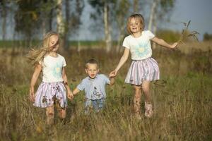 Lycklig familj systrar och liten bror på en sommar äng. foto