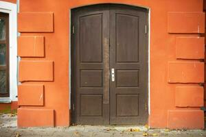 brun gammal dörr i ett orange betong vägg. foto