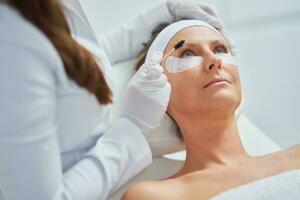 kvinna har kosmetologi ögonbryn behandling i skönhet salong foto