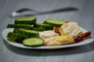 friterad ägg med korv och skivad gurkor foto